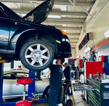 An ABS Unlimited auto technician works underneath a car