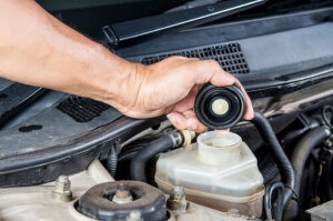 Is Brake Fluid Flush Necessary for Fairfax, VA Drivers | ABS Unlimited. Car mechanic checking brake fluid inlet during car maintenance.
