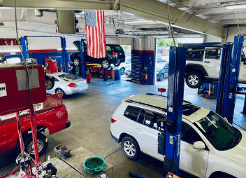 different vehicles on lifts in shop bay area | ABS Unlimited in Fairfax, VA
