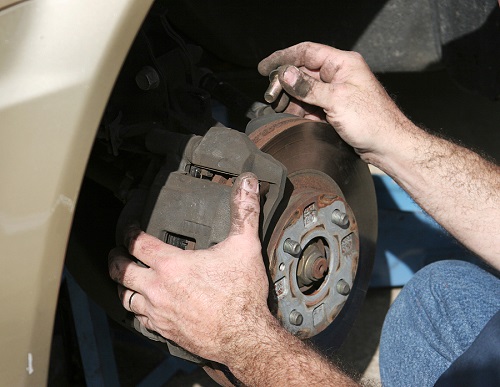 Brake Repair | ABS Unlimited in Fairfax, VA. Closeup image of a mechanic repairing a car brake.